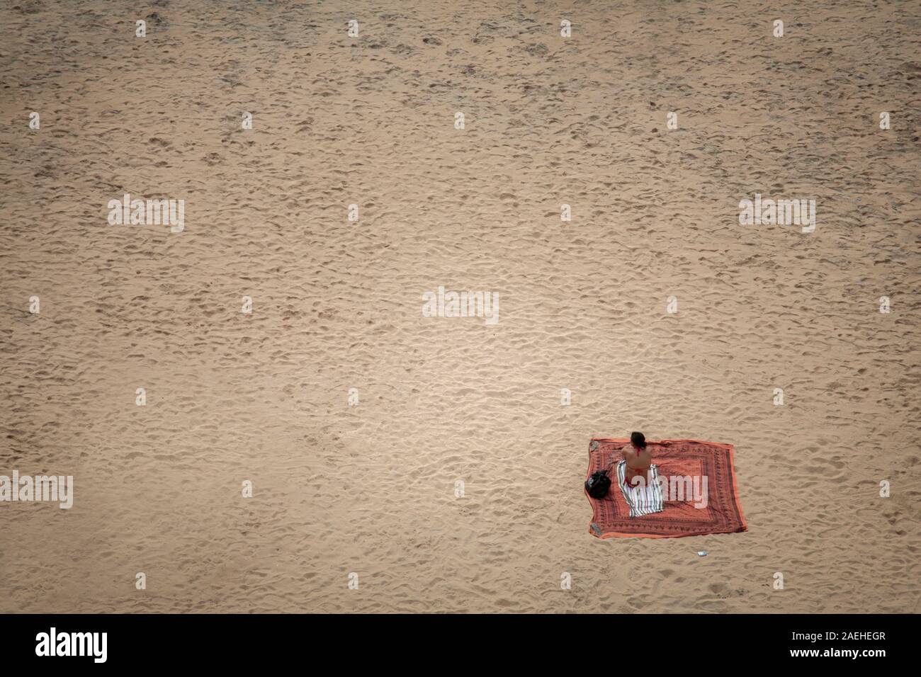 lonely woman sitting on sandy beach Stock Photo