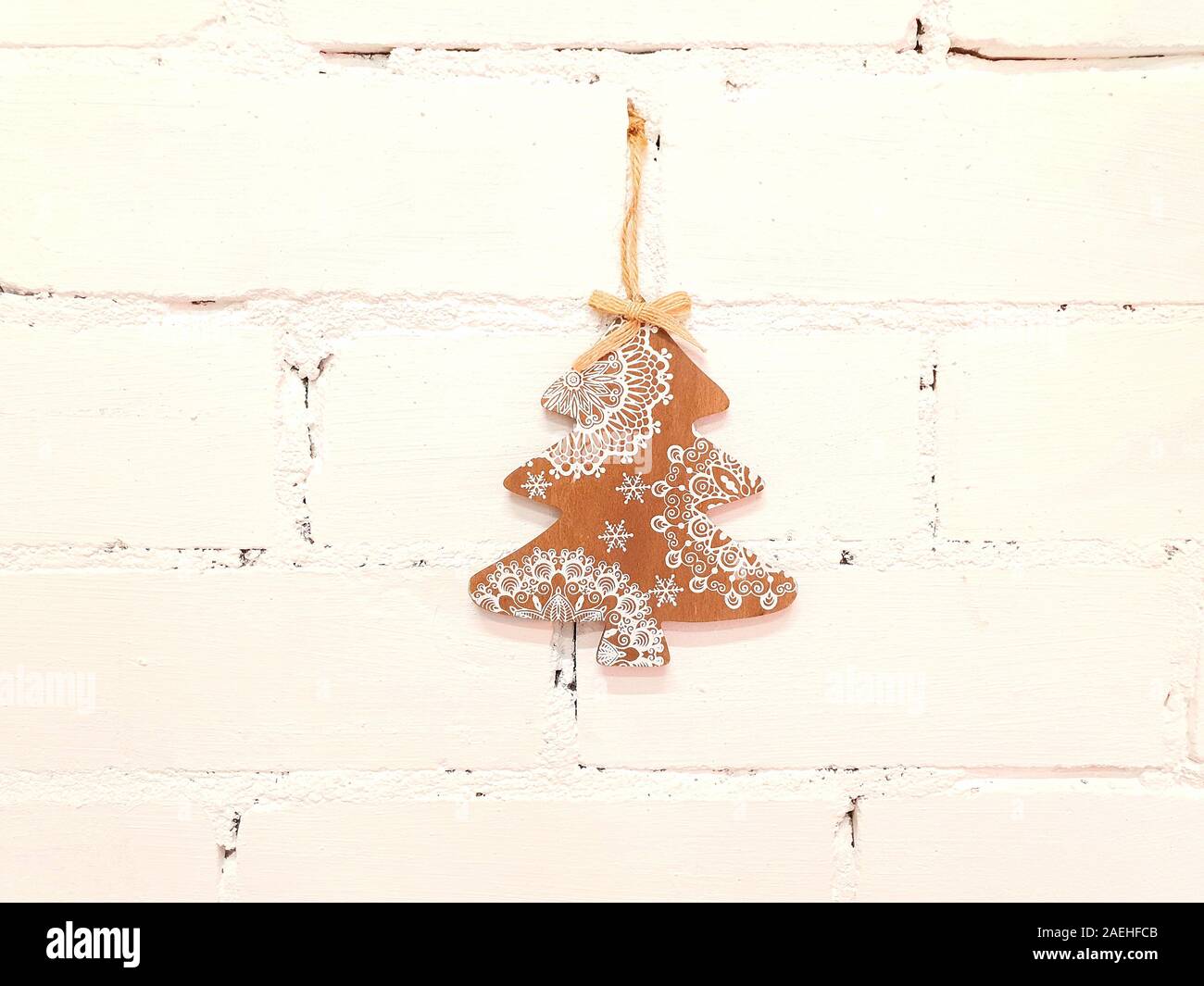 Christmas, small wooden tree. The decorations are attached to the wall in white and serve as decoration in the interior of the house. Stock Photo