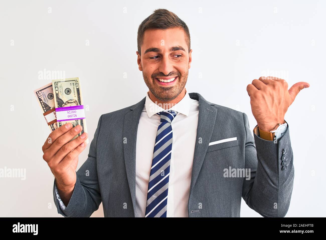 Young handsome business man holding bunch of dollars banknotes over ...
