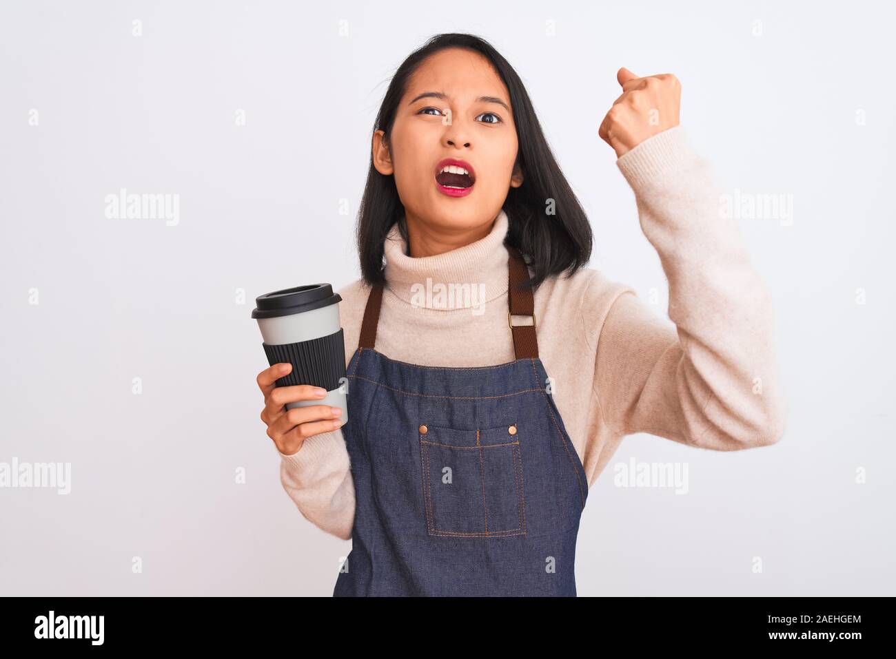 Beautiful barista chinese woman wearing apron holding coffee over isolated white background annoyed and frustrated shouting with anger, crazy and yell Stock Photo