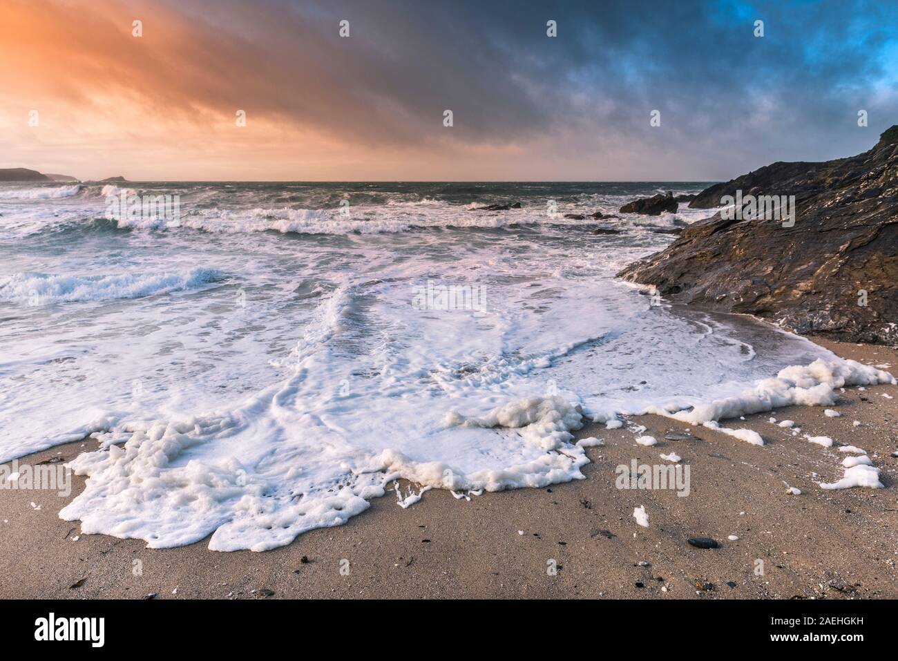 Evening light over Little Fistral as the windy weather blows spume on to the shore in Newquay in Cornwall. Stock Photo