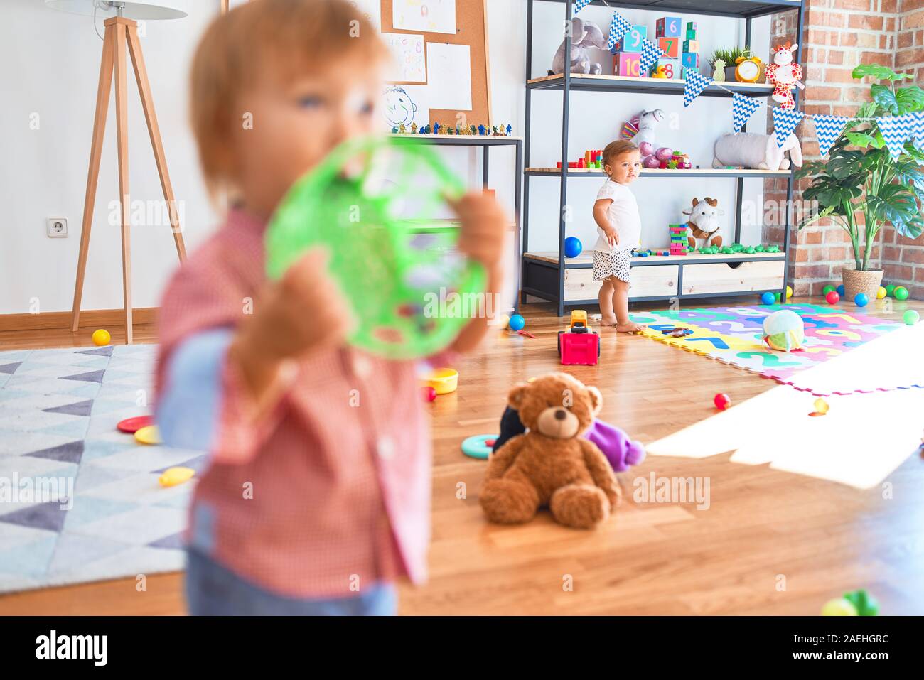 Adorable toddlers playing around lots of toys at kindergarten Stock Photo