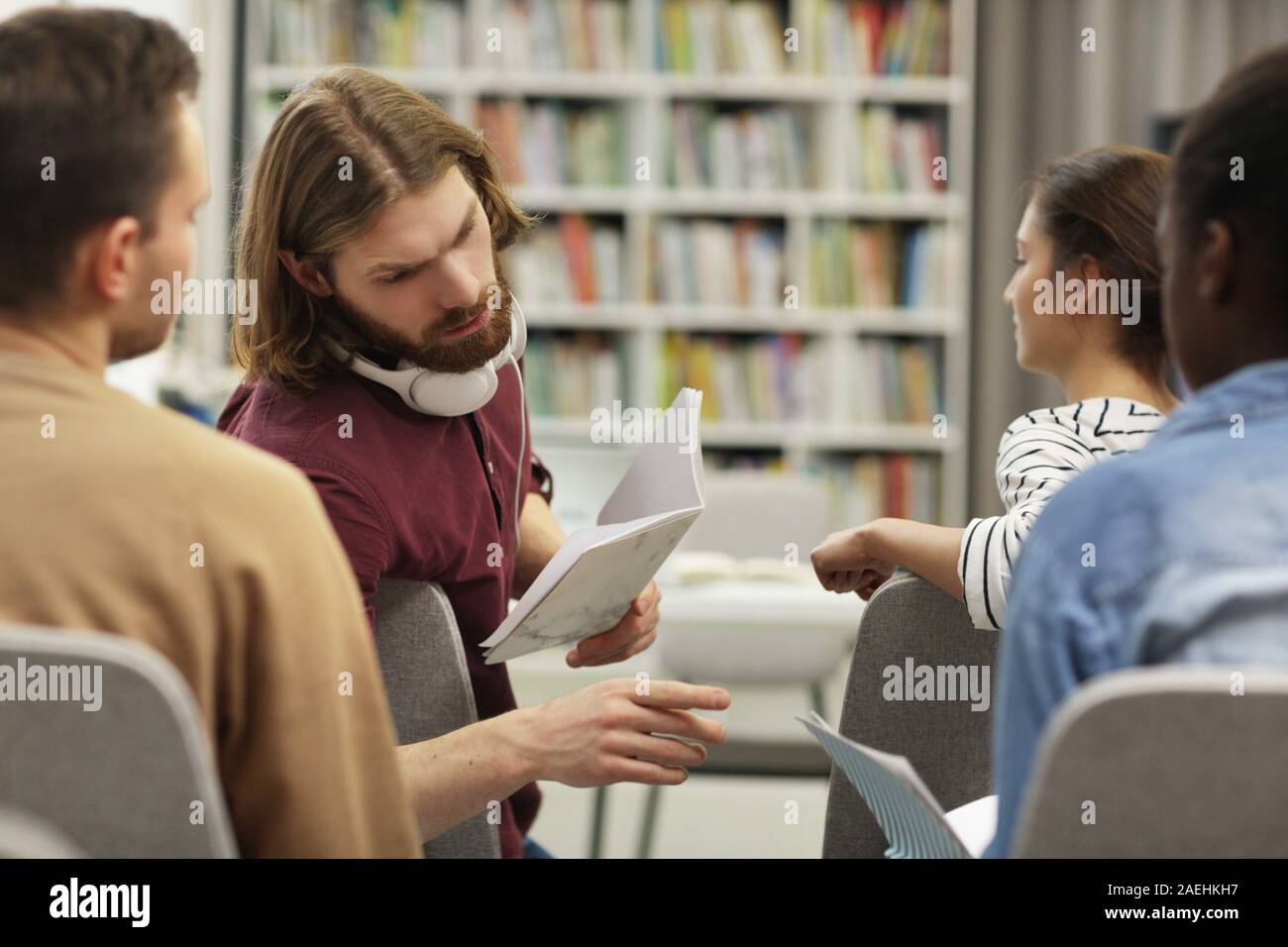 Young people discussing something and working in team while sitting at business seminar Stock Photo