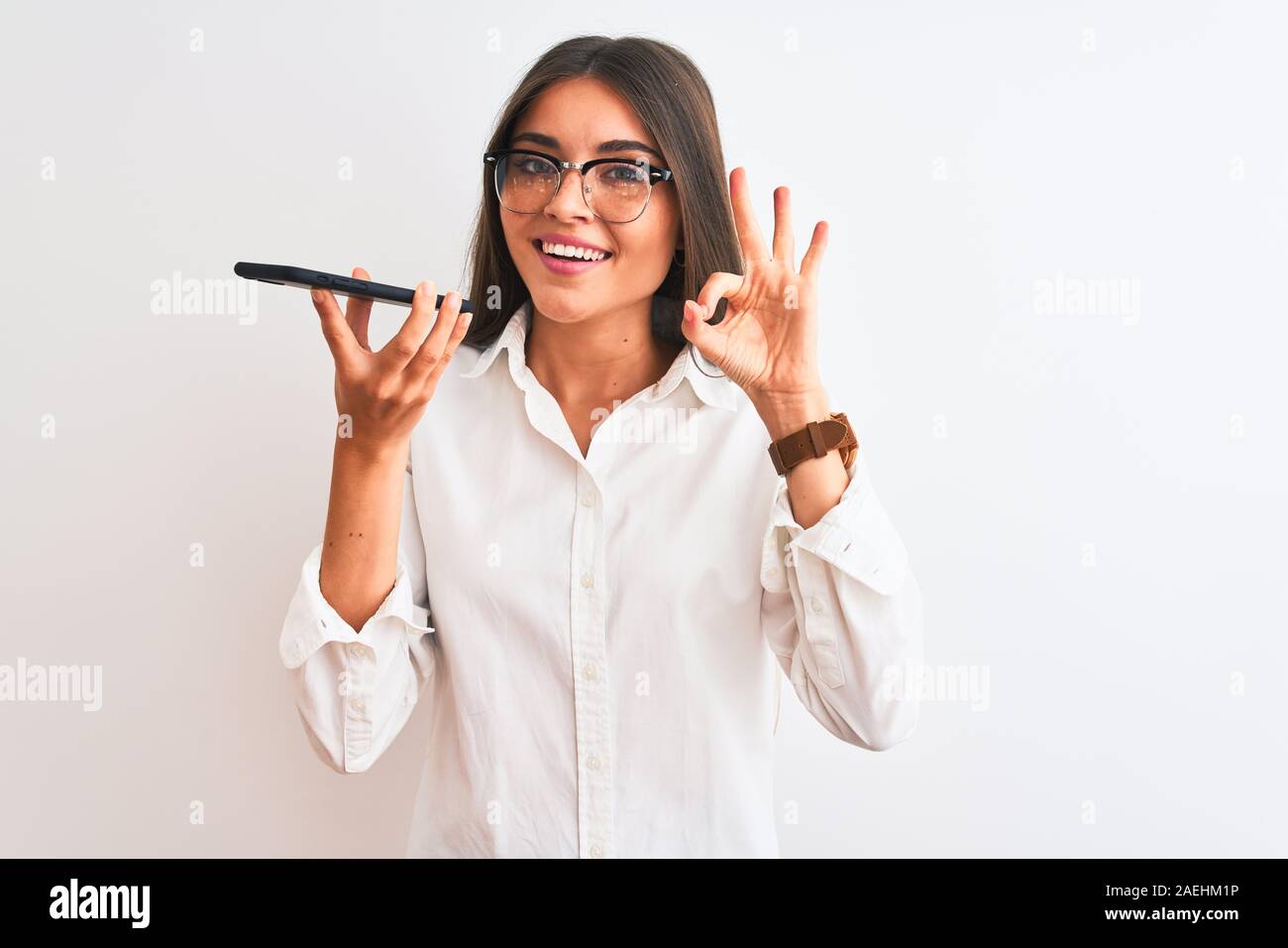 Woman wearing glasses sending message on smartphone over isolated white ...