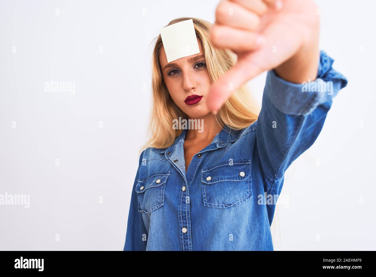 Beautiful woman with reminder sticker paper on forehead over isolated ...