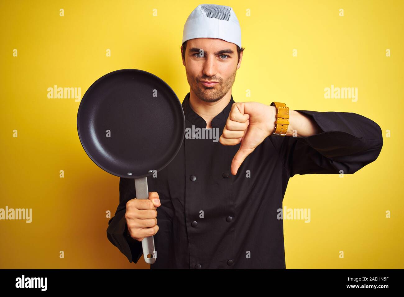 Young chef man wearing uniform and hat holding cook pan over isolated ...
