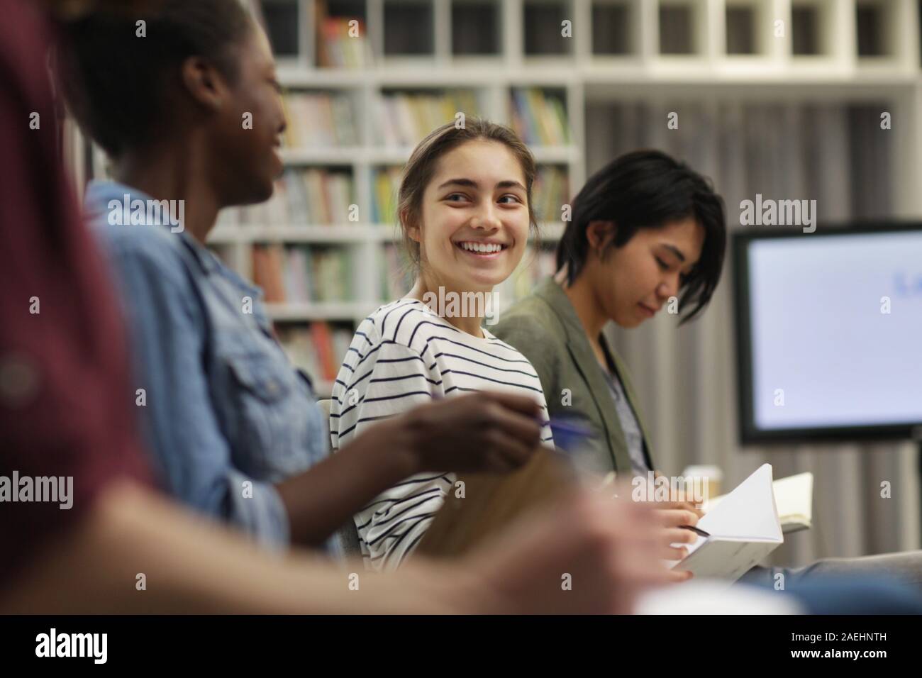 Young businesswoman sitting and smiling while talking to her colleagues during a seminar Stock Photo