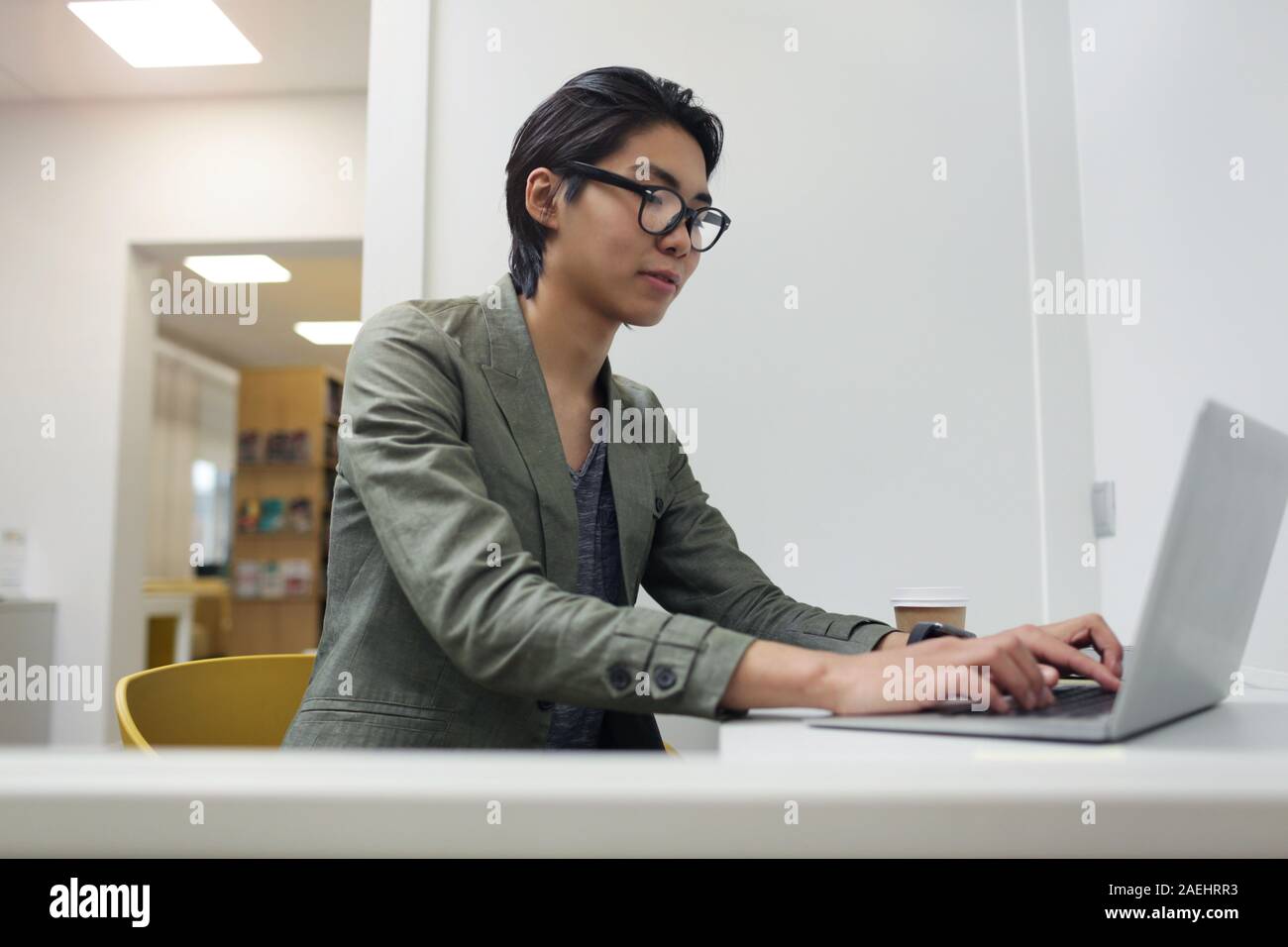 Asian young businessman sitting at his workplace and typing on laptop computer at office Stock Photo