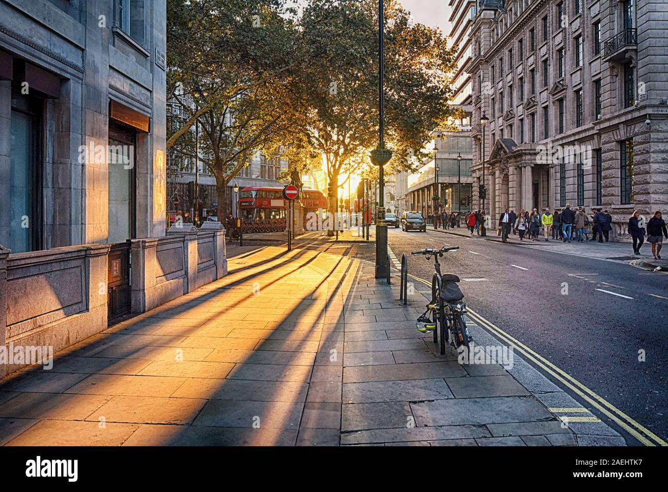 Looking towards the setting sun on Pall Mall East with bus, taxi and bicycle Stock Photo