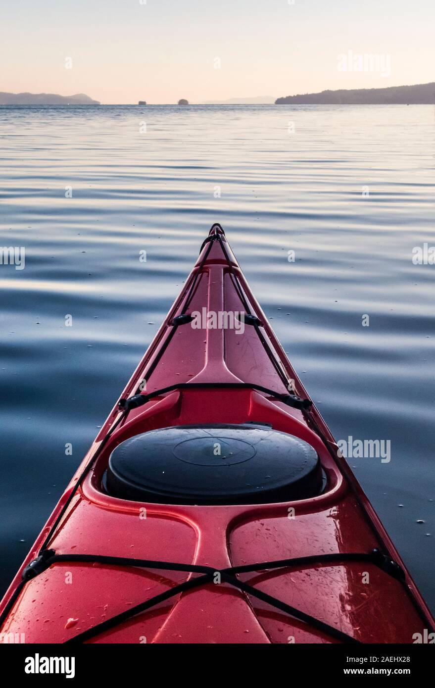 The bow of a sea kayak on glassy water in the Gulf Islands of British Columbia, Canada. Ganges Harbor, Salt Spring Island. Stock Photo