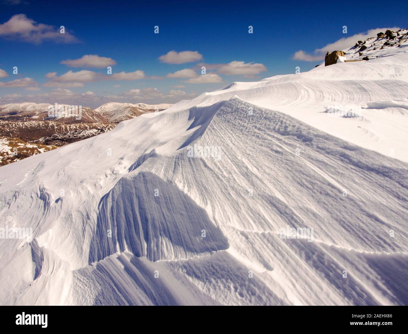 Snow shaped and scoured by a strong wind when it fell, above Wrynose Pass in the Lake District, Cumbria, UK. Stock Photo