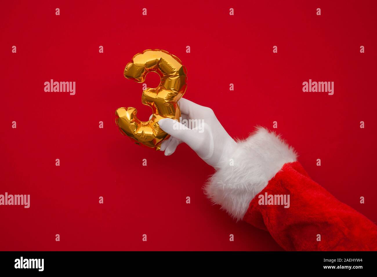 12 days of christmas. Santa hands holding 3rd day balloon on red background Stock Photo