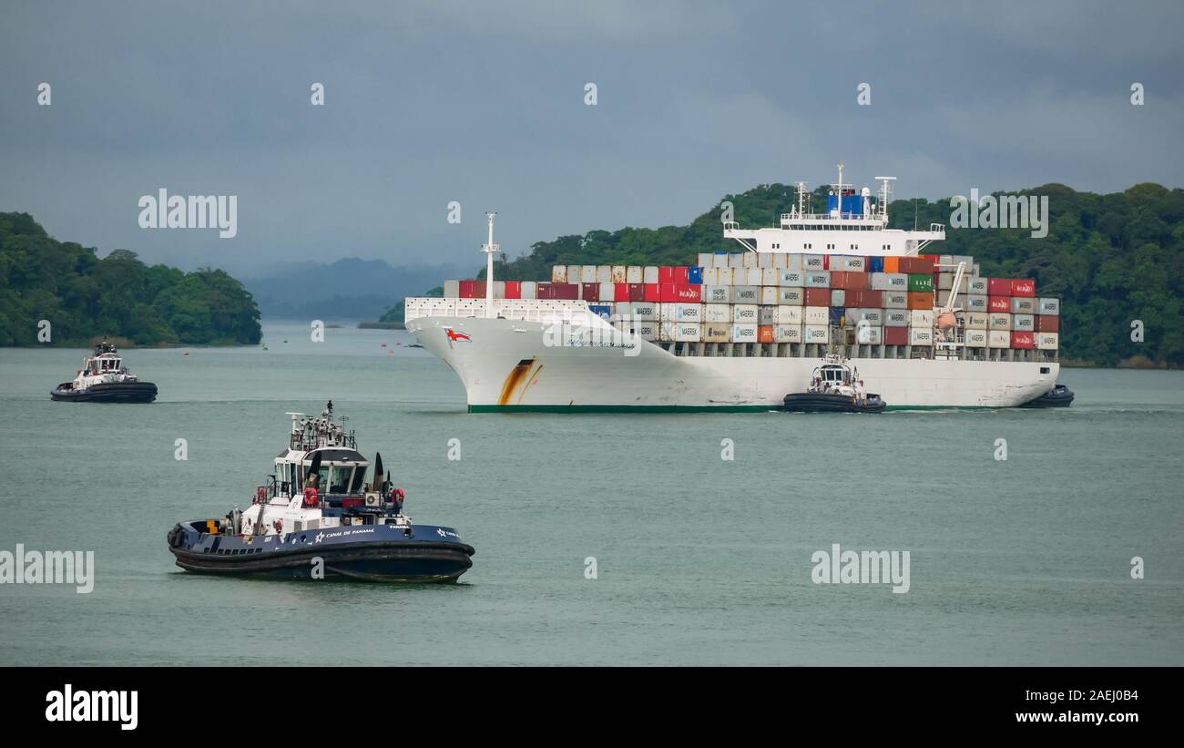 Container ship (Safmarine Nokwanda) surround by the Panama Canal tugboats in Gatun lake waiting to enter the Agua Clara locks. Stock Photo