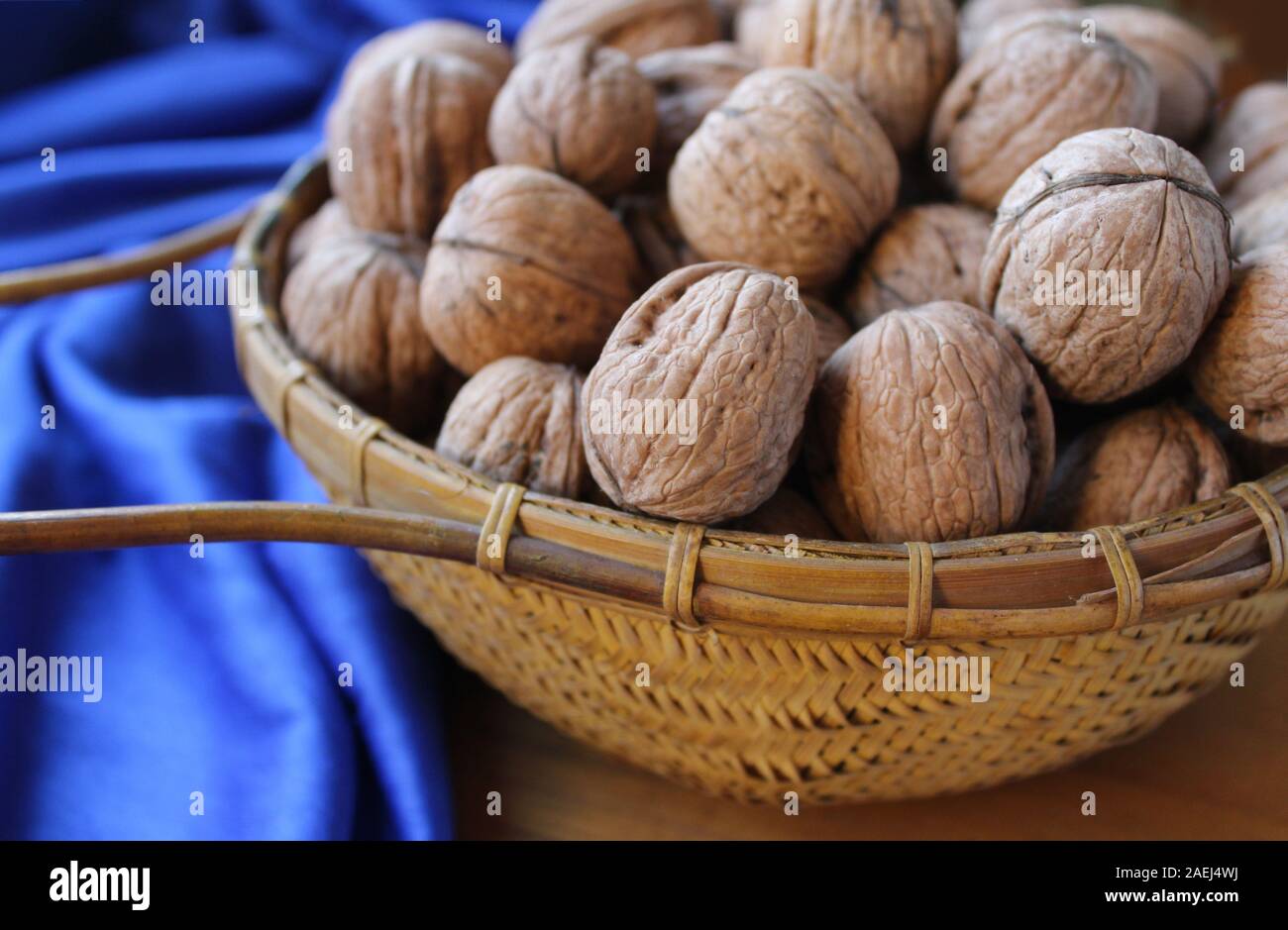 A basket full of walnuts in shells, in close up with a classic blue background. Rustic nature food. Stock Photo