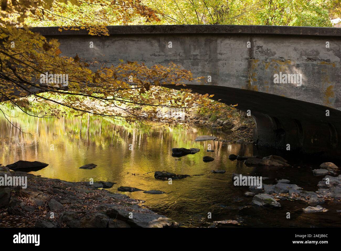 Small bridge arches across the Mill River in Williamsburg, Massachusetts in the fall. Stock Photo