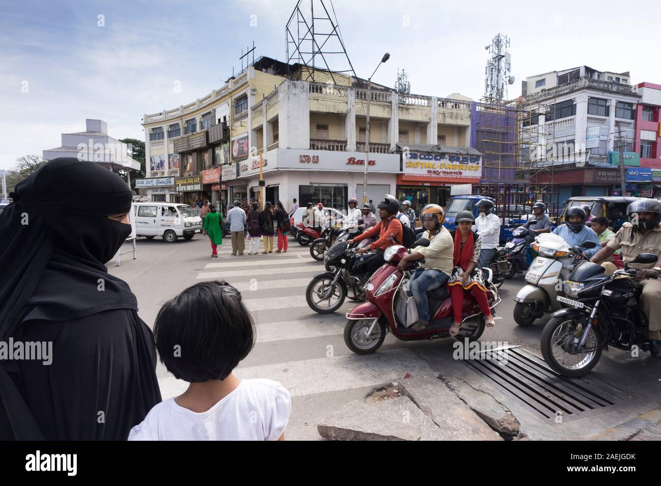 Parent and child trying to cross the road in Mysore, India Stock Photo