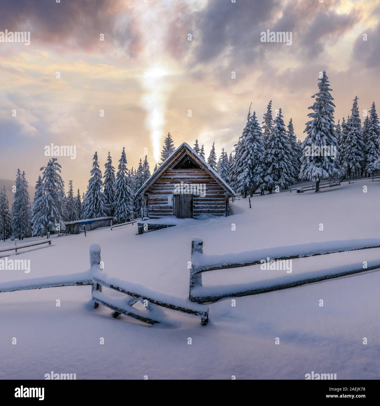 Fantastic winter landscape with wooden house in snowy mountains. Smoke comes from the chimney of snow covered hut. Christmas holiday concept Stock Photo