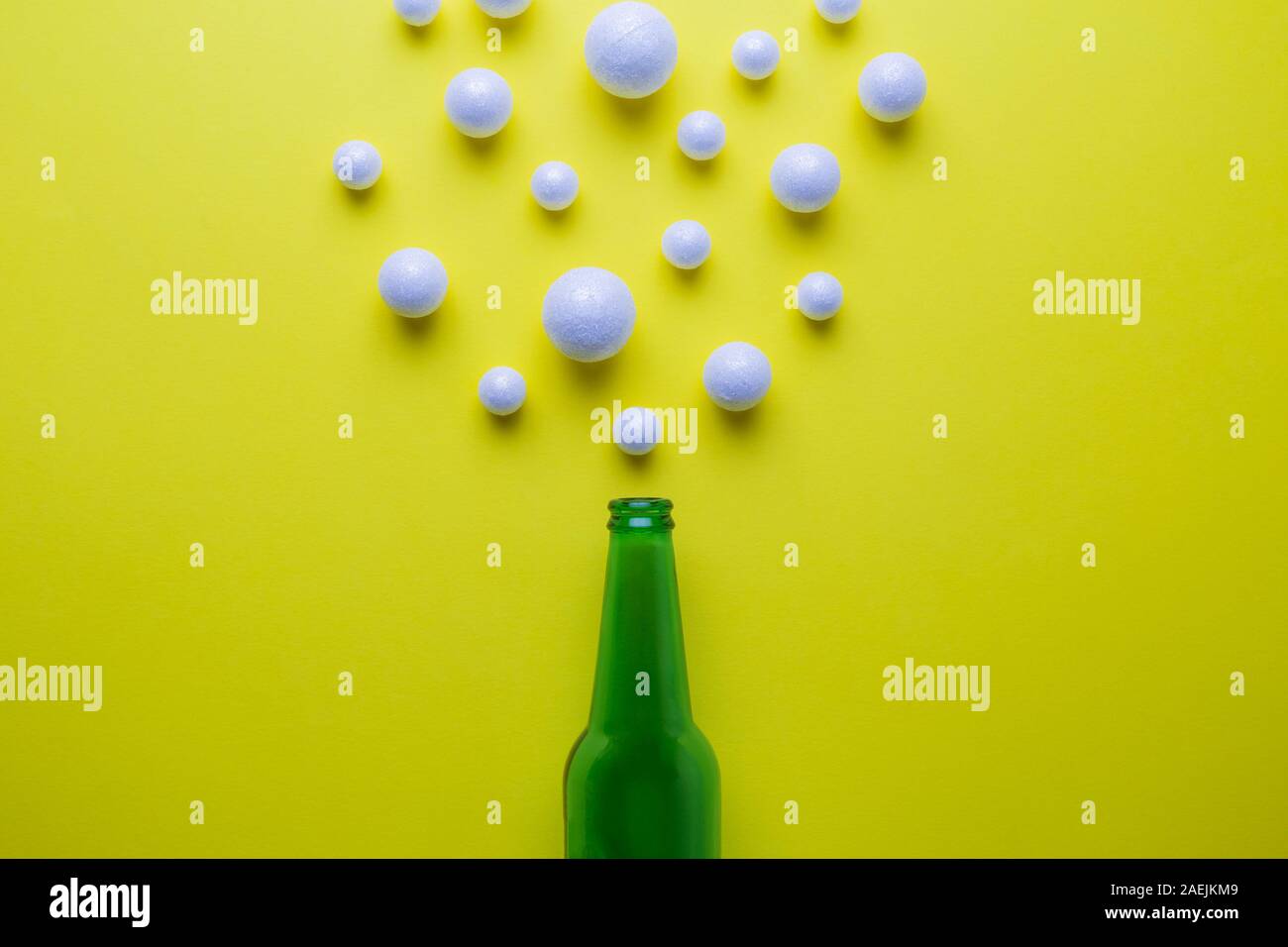 Beer abstract made of green bottle and styrofoam balls on yellow. Stock Photo
