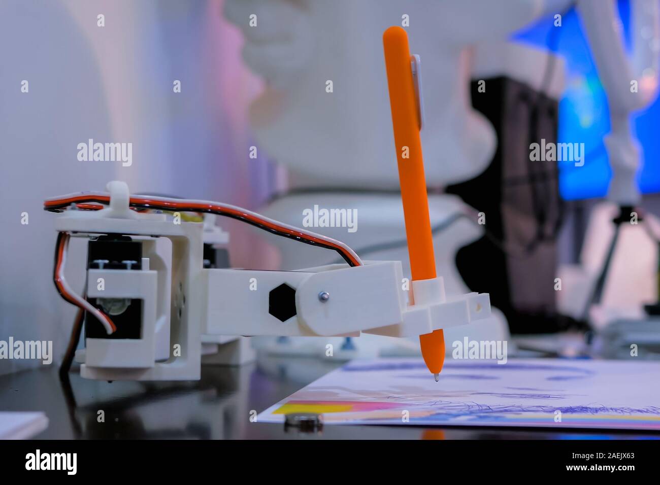 Robotic arm with orange pen drawing portrait at robot futuristic
