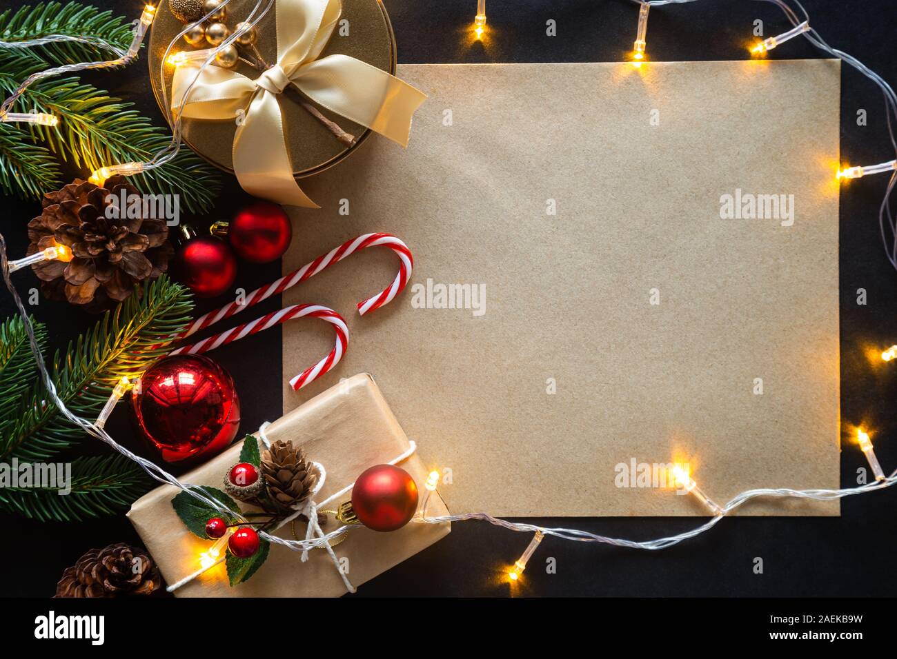 Holiday Christmas card background with festive decoration ball, stars, snowflakes, gift box, pine cones on a black background from Flat lay, top view. Stock Photo