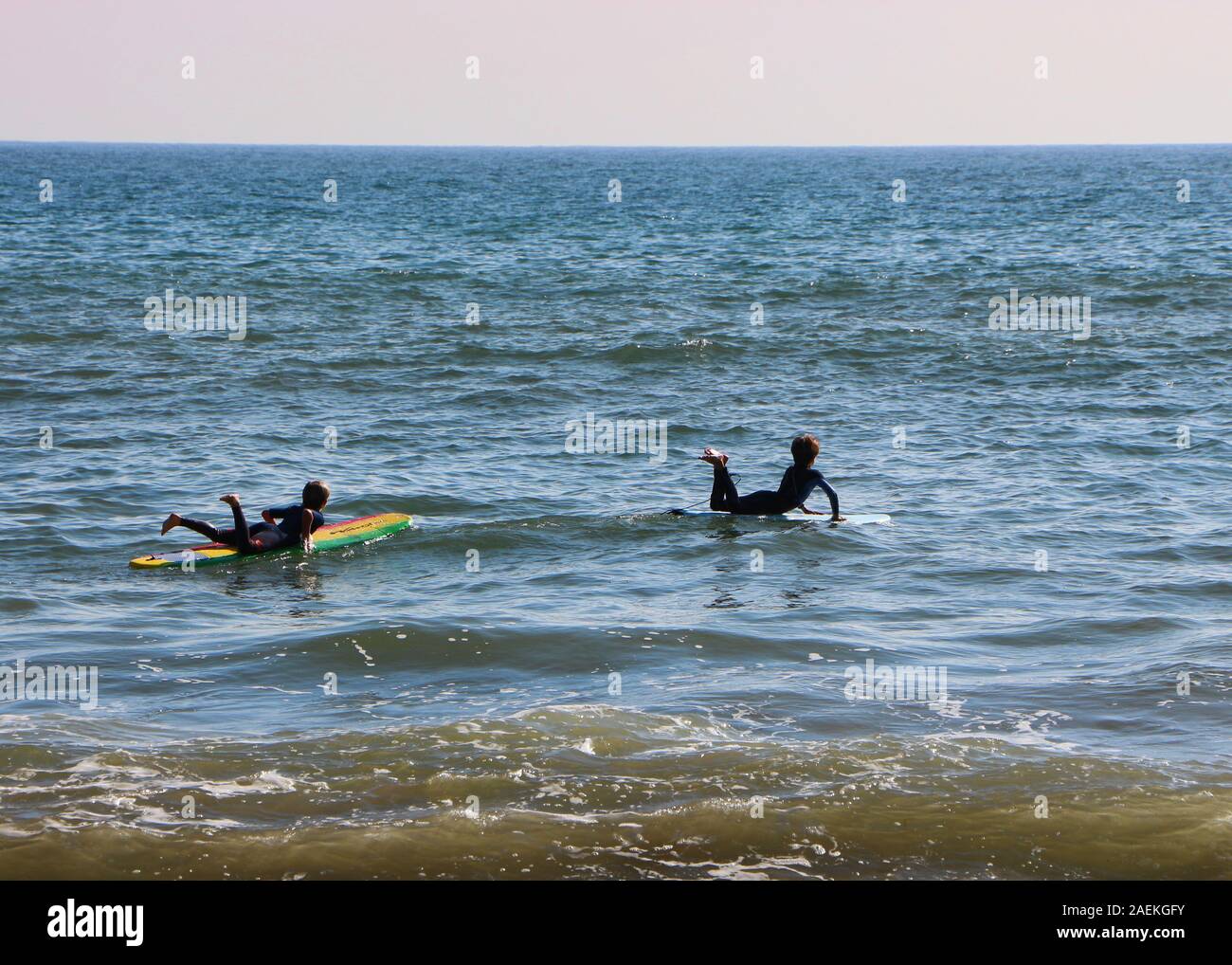 Two young surfers are excited heading towards the spiritual connection with the Pacific Ocean on Corral Canyon Beach, Malibu, CA 90265 Stock Photo