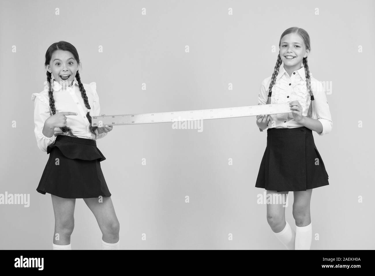 Close or far. Measuring skills. Measuring distance. Measuring equipment. Kids students study math. Knowledge day. Schoolgirls school uniform hold big ruler. Geometry school lesson. Teamwork concept. Stock Photo