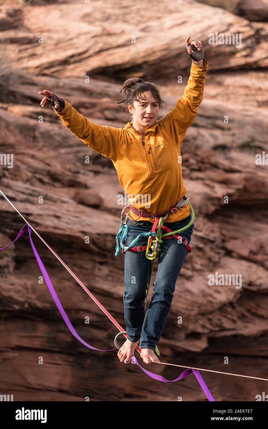 A young woman slacklining or highlining hundreds of feet above Mineral Canyon near Moab, Utah during a highline gathering. Stock Photo