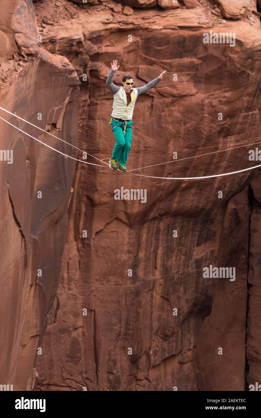 A young man slacklining or highlining hundreds of feet above Mineral Canyon near Moab, Utah during a highline gathering. Stock Photo