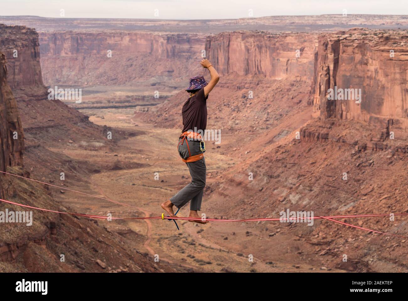 A young man slacklining or highlining hundreds of feet above Mineral Canyon near Moab, Utah during a highline gathering. Stock Photo