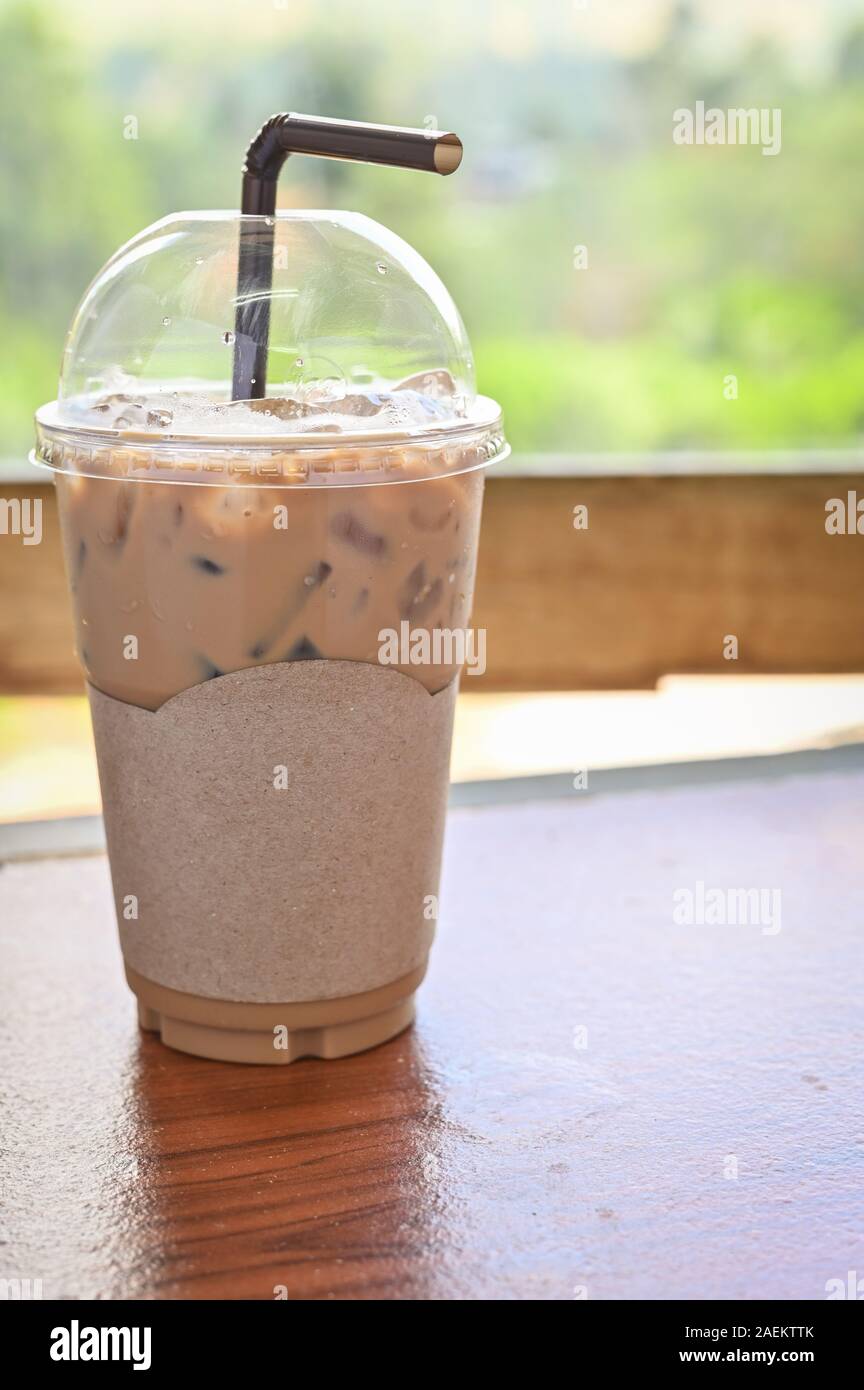 Iced coffee in take away cup plastic glass on the wood table in cafe with clipping path on blank label paper for mockup cafe logo Stock Photo