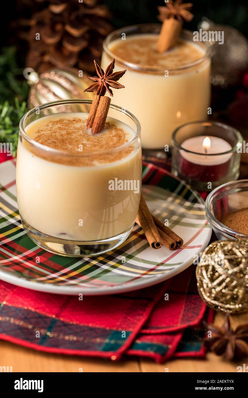 A close up view of two glasses of egg nog sprinkled with cinnamon and garnished with cinnamon sticks and star anise. Stock Photo