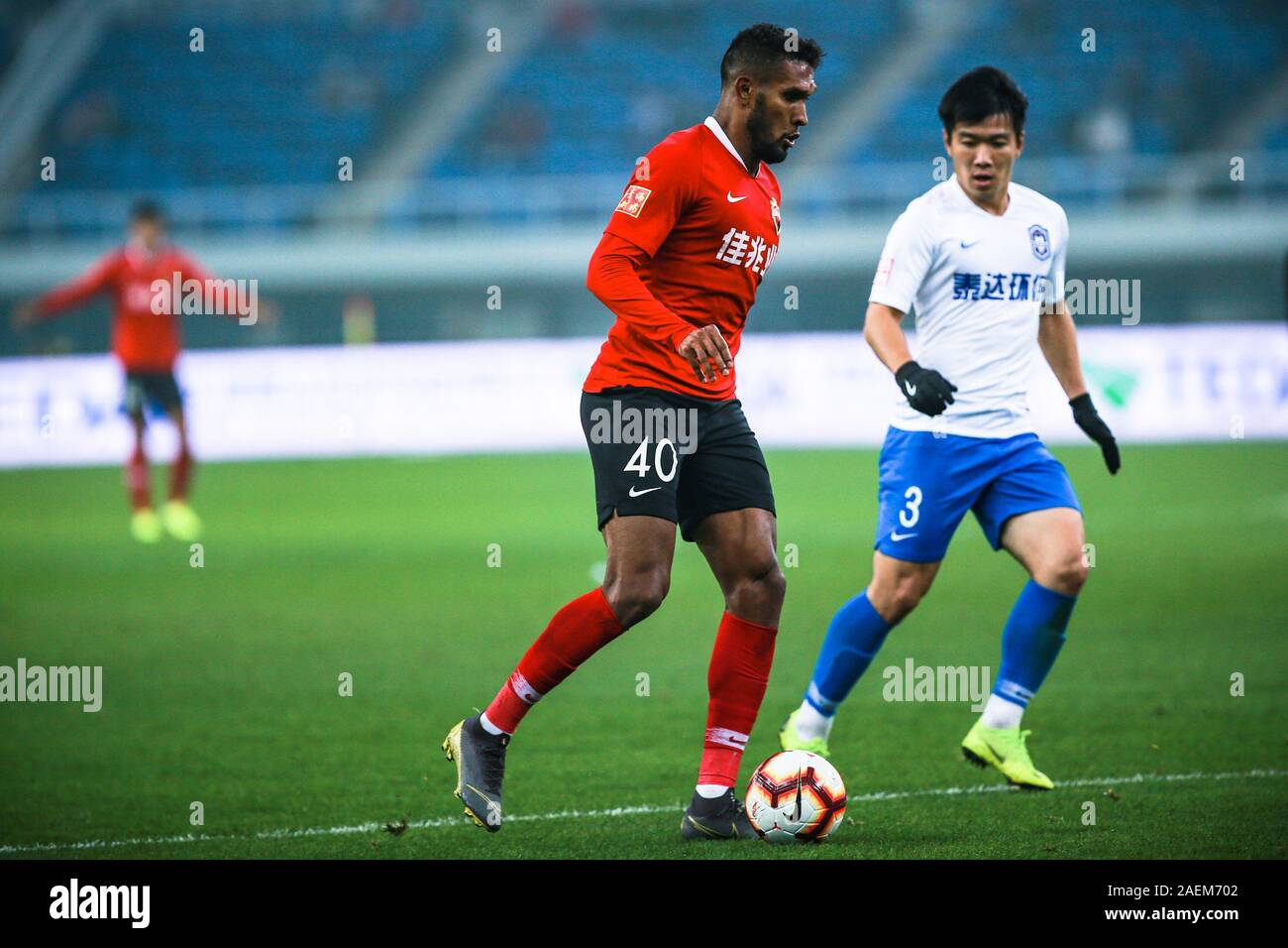 Brazilian-born Portuguese football player Dyego Sousa of Shenzhen F.C., left, keeps the ball during the 28th round match of Chinese Football Associati Stock Photo