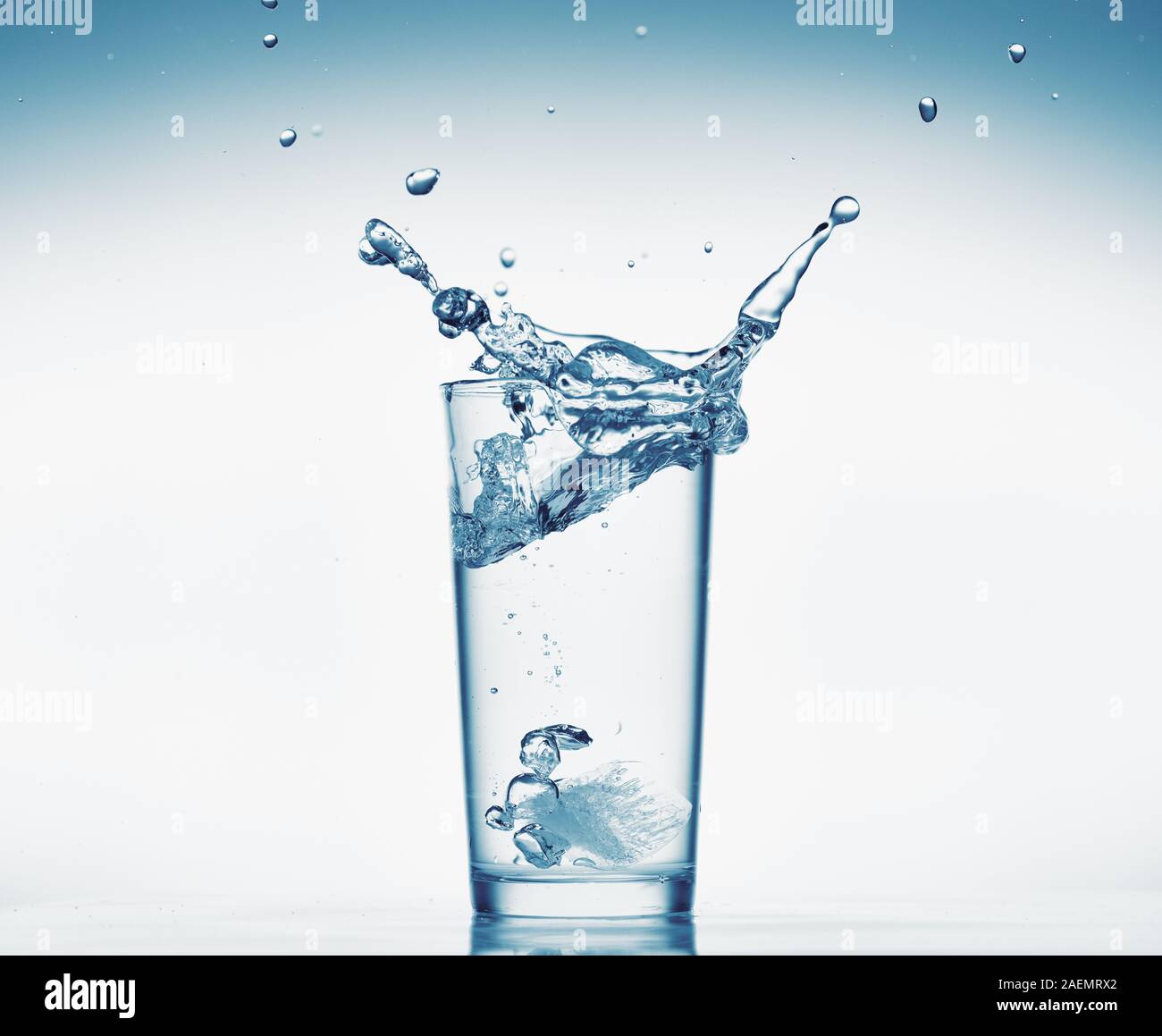 one glass of water with splash from falling ice cube, white background