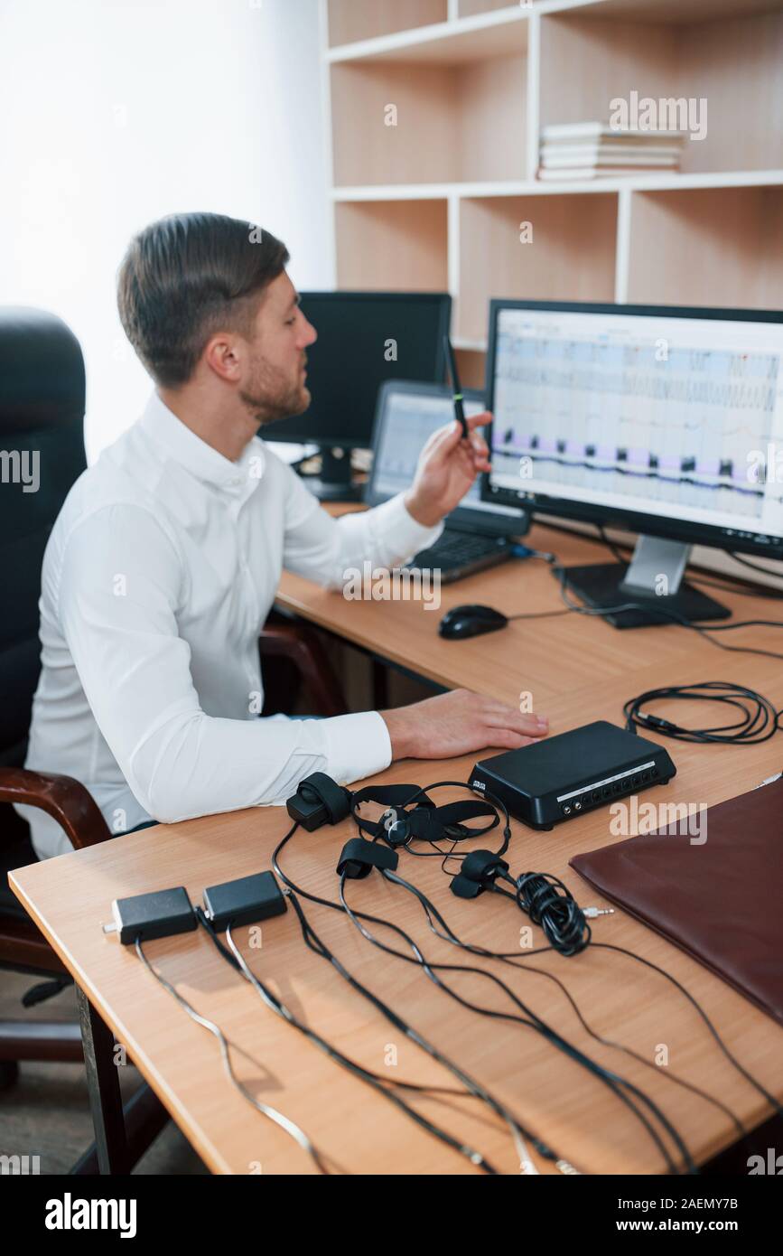 Vertical photo. Polygraph examiner works in the office with his lie detector's equipment Stock
