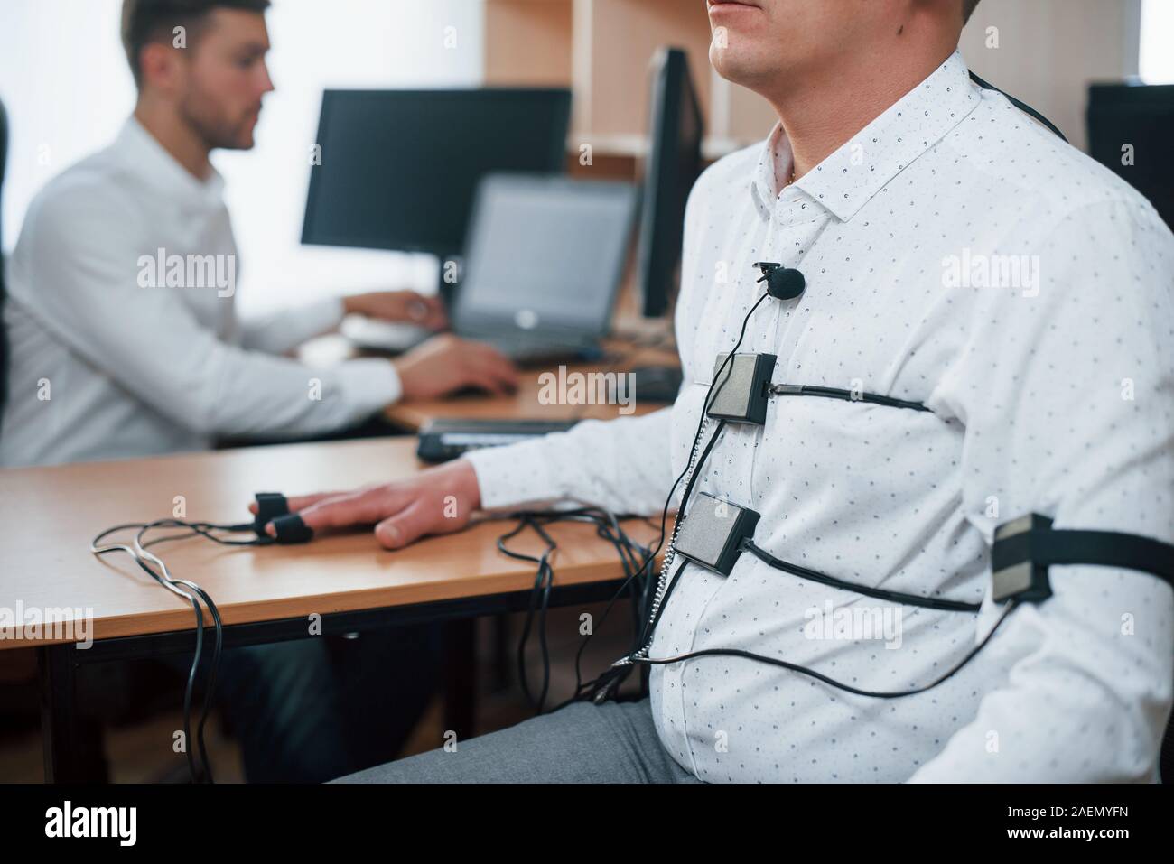 You did not know what your colleague thought. Suspicious man passes lie detector in the office. Asking questions. Polygraph test Stock Photo