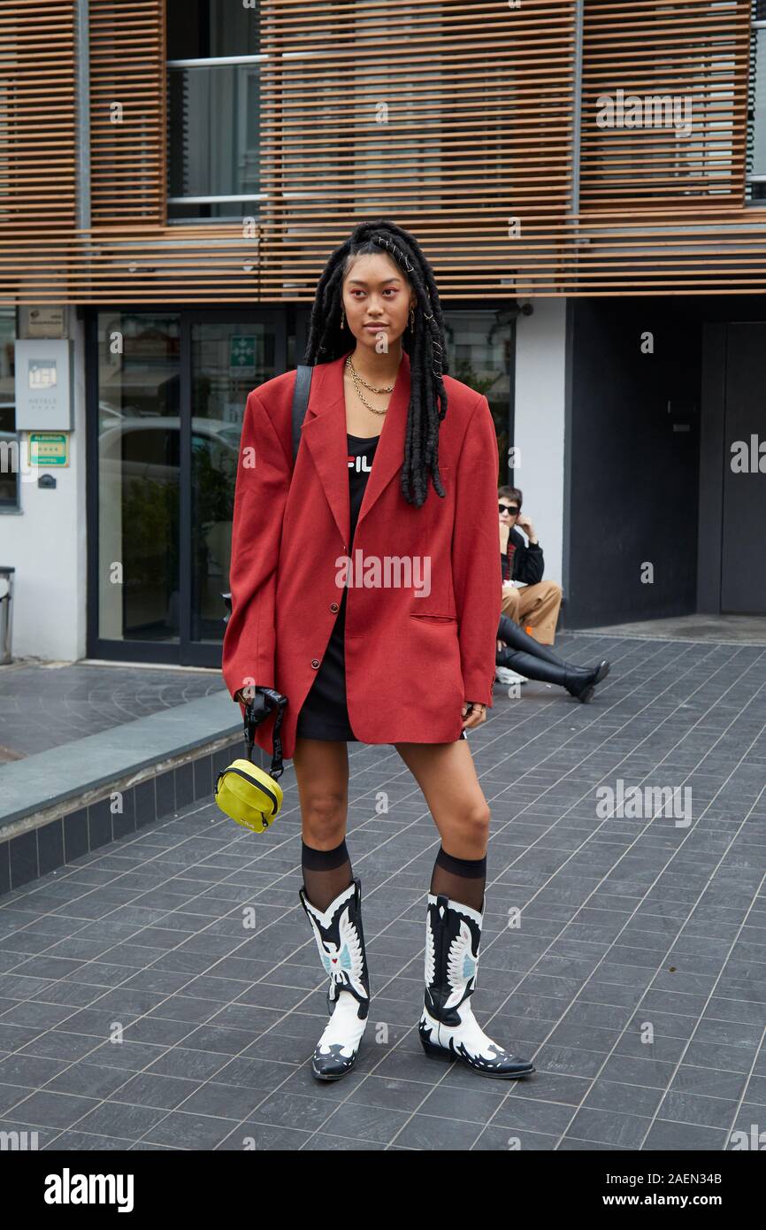 MILAN, ITALY - SEPTEMBER 22, 2019: Woman with red jacket and cowboy boots before Fila fashion show, Milan Fashion Week street style Stock Photo