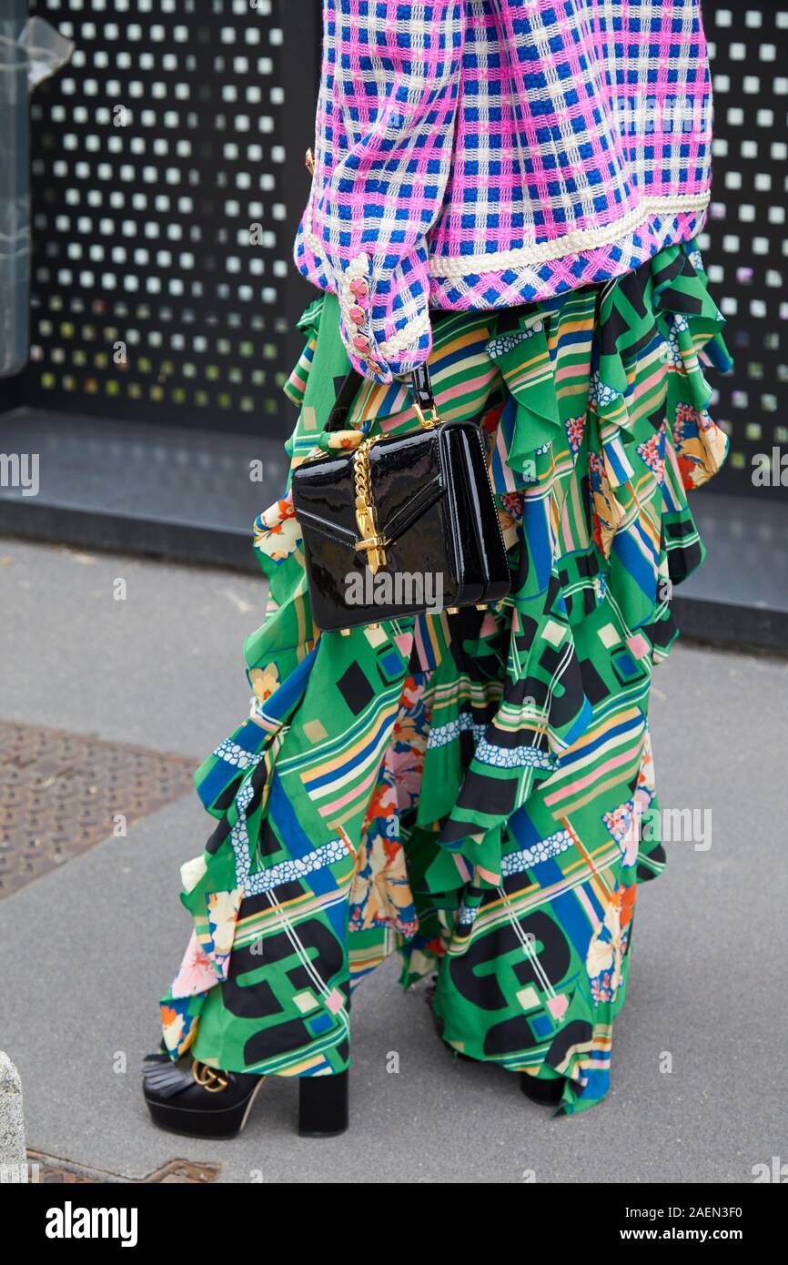 MILAN, ITALY - SEPTEMBER 22, 2019: Woman with black patent leather bag with golden belt and green skirt before Gucci fashion show, Milan Fashion Week Stock Photo