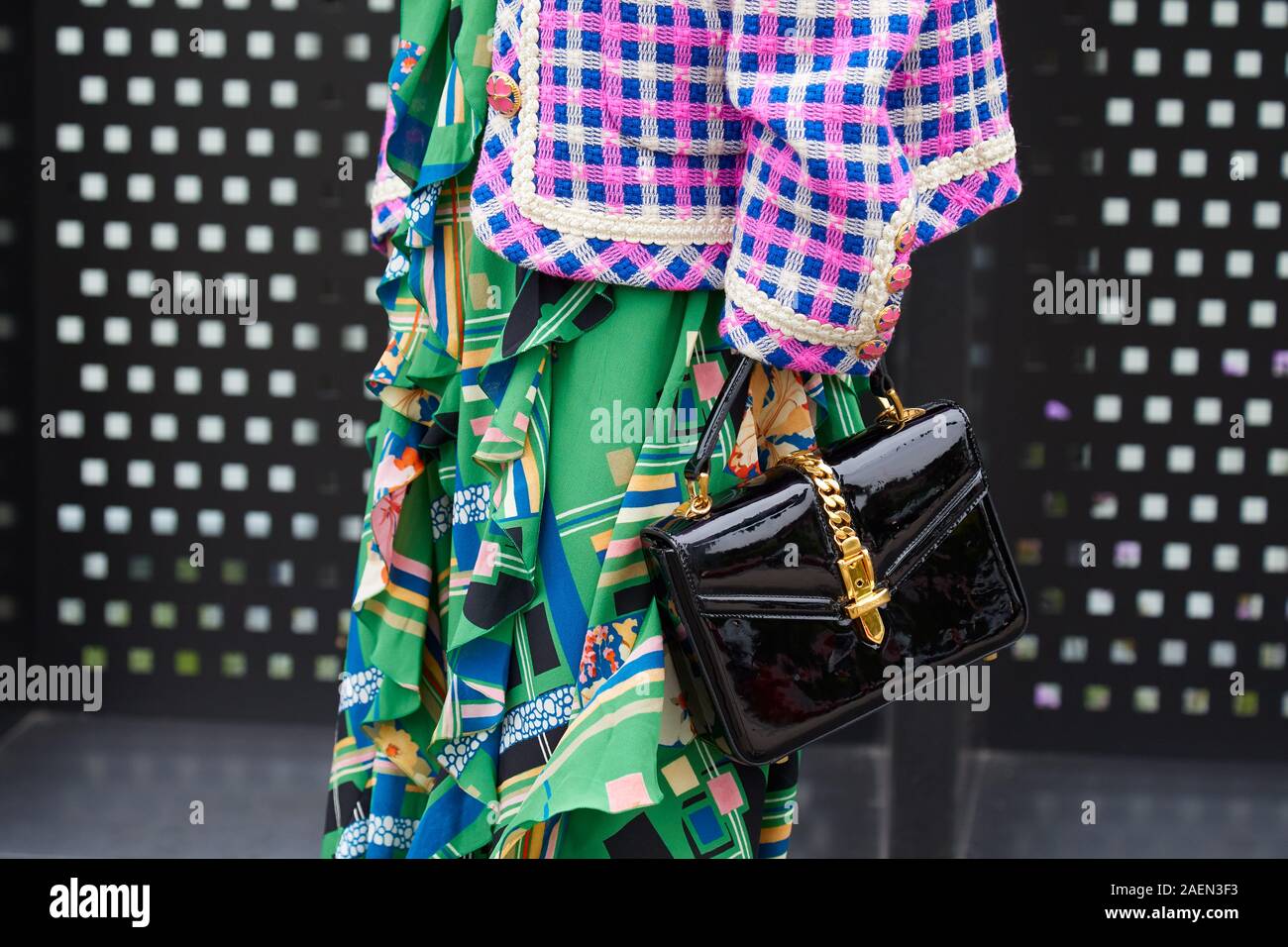 MILAN, ITALY - SEPTEMBER 22, 2019: Woman with black patent leather bag with golden belt and green skirt before Gucci fashion show, Milan Fashion Week Stock Photo