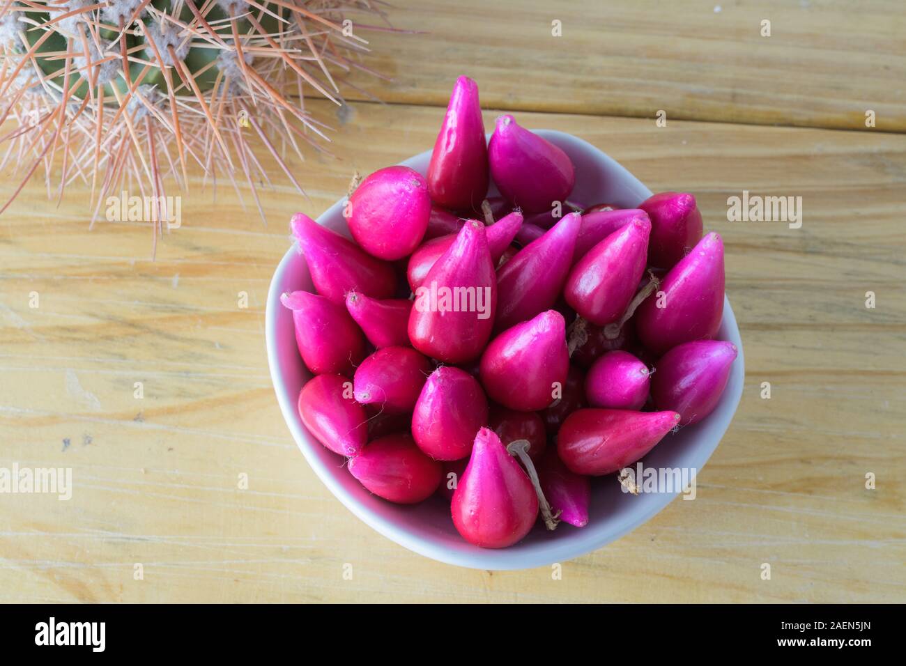 Pitiguey fruit group in white bowl on wood table with Cactus. Top down Stock Photo