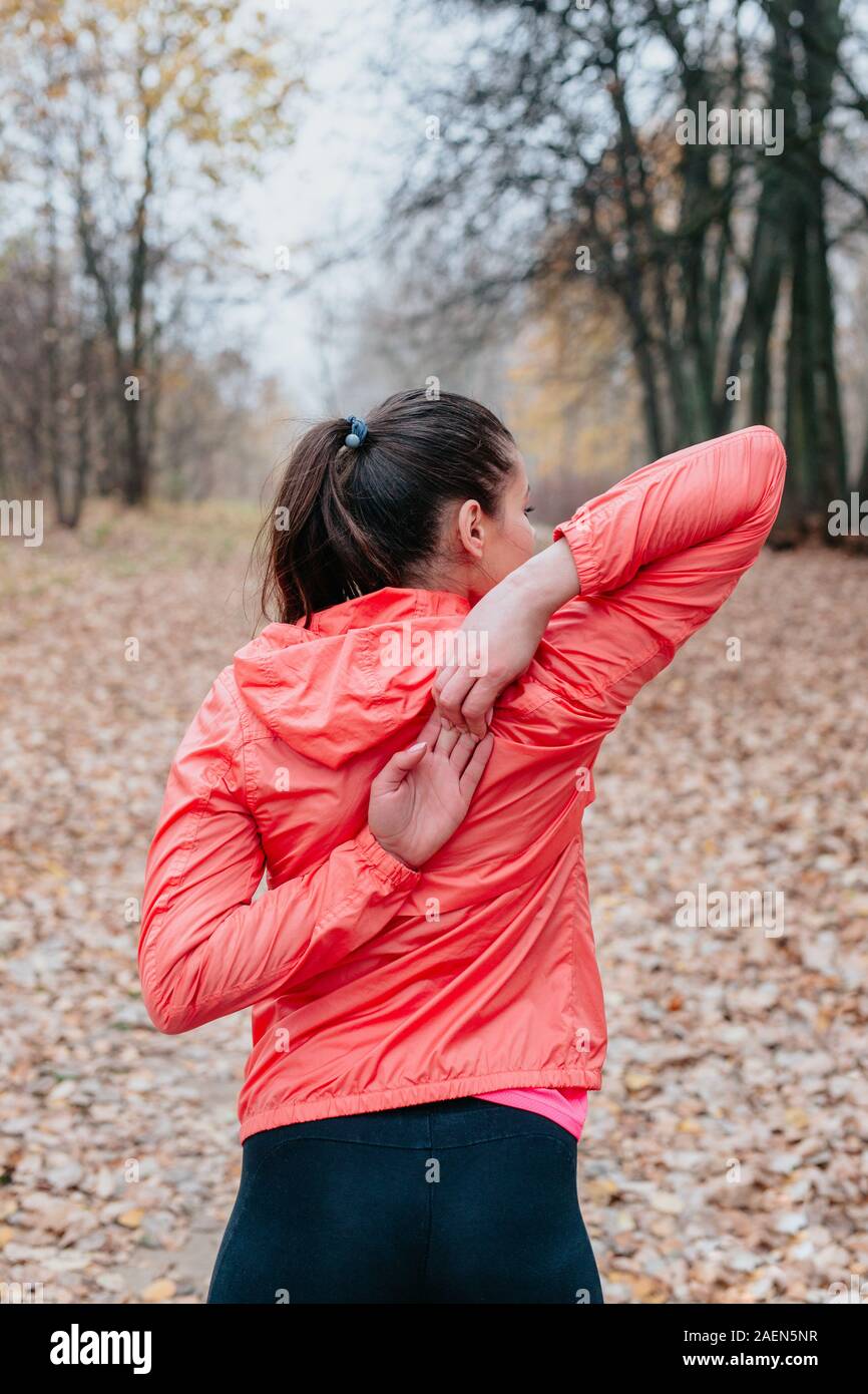 Young woman stretching before her run outdoors on a cold autumn day Stock Photo
