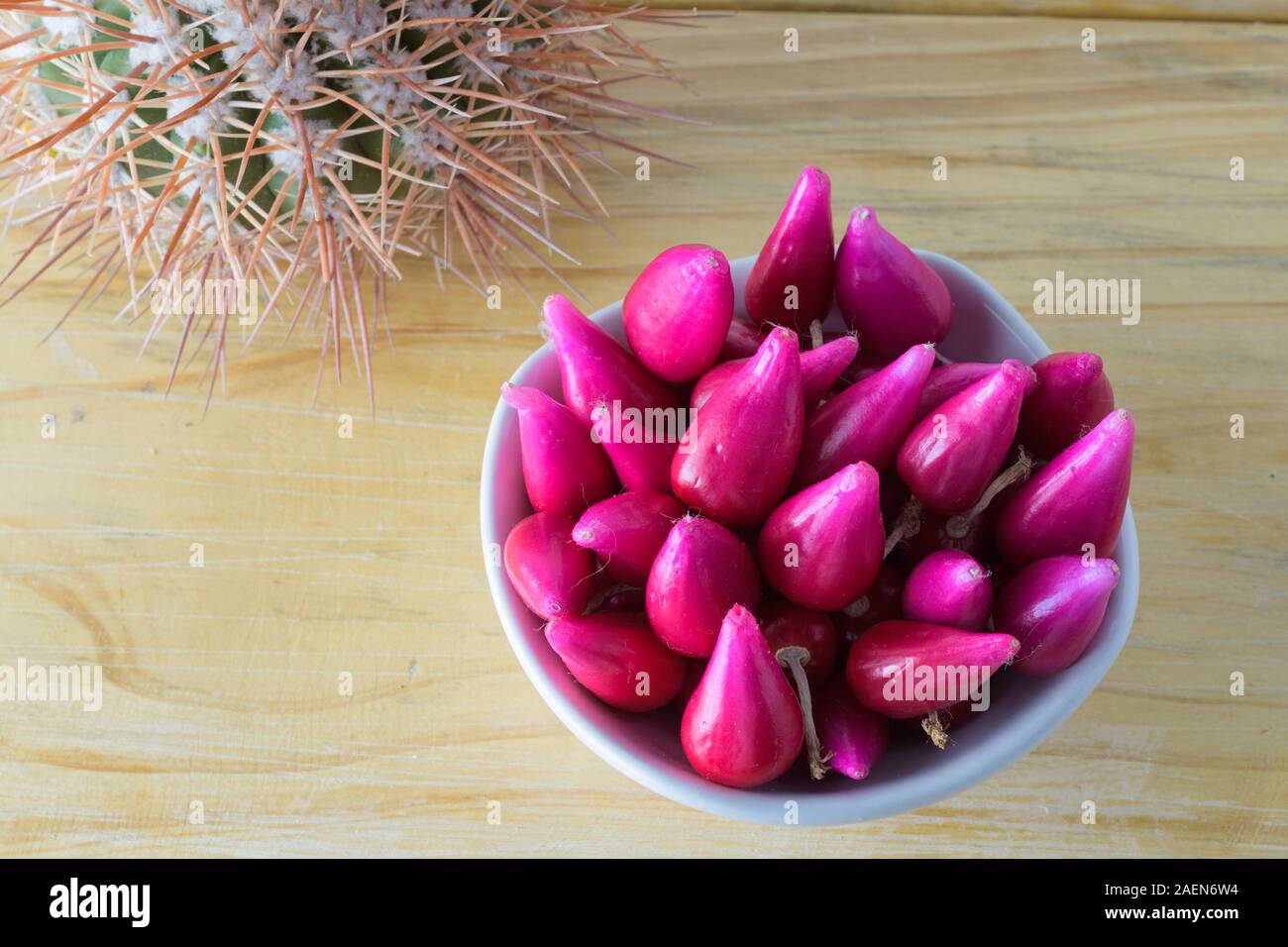Pitiguey fruit group in white bowl on wood table with Cactus. Top down Stock Photo