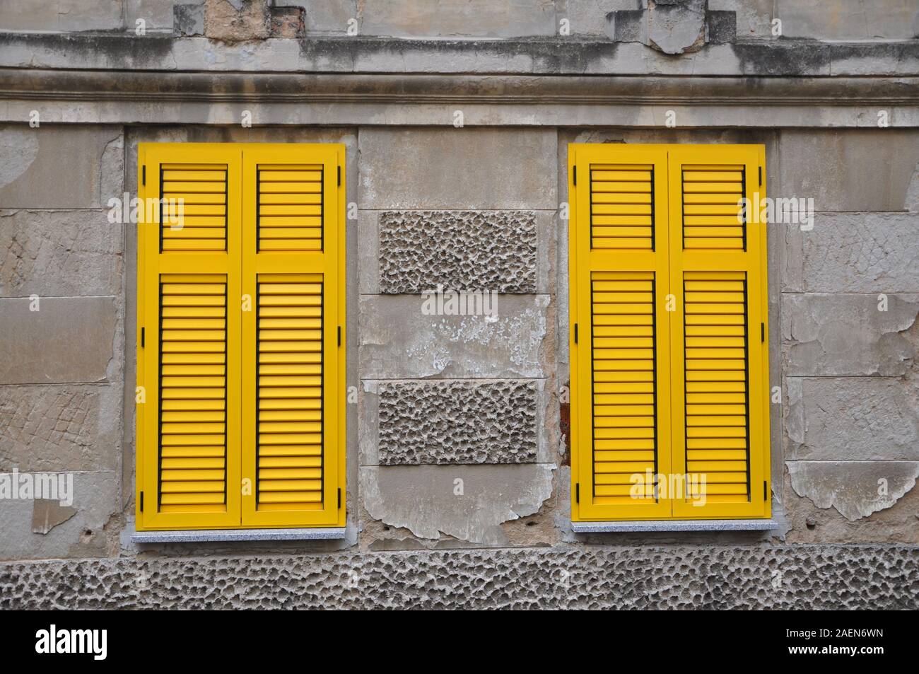 Yellow closed shutters on old grey building Stock Photo