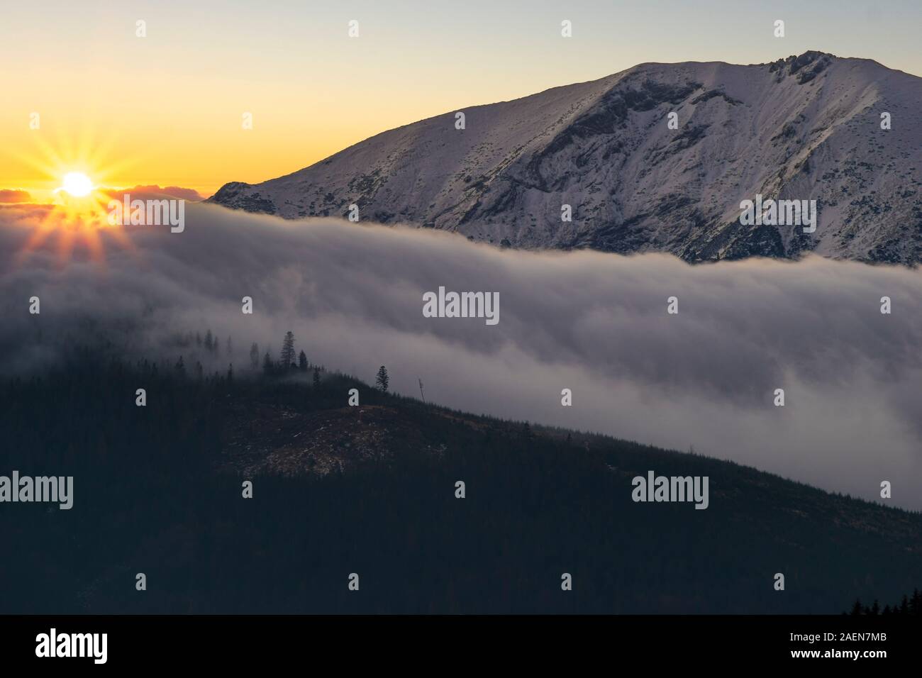 sunrise over the embankment from clouds overflowing over the tops of the mountains Stock Photo