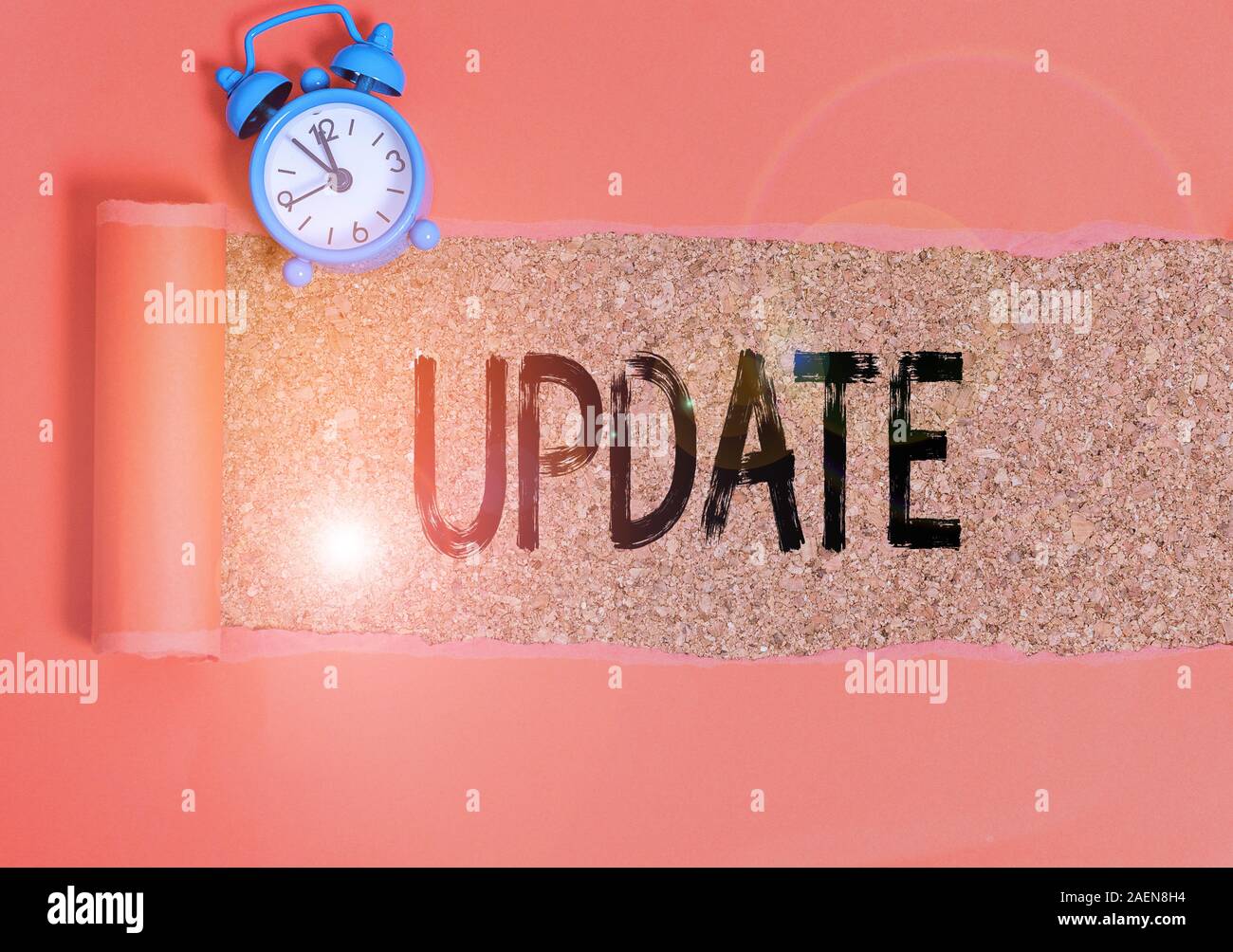 Conceptual hand writing showing Update. Concept meaning by adding new information or making corrections Up to date Alarm clock and torn cardboard on a Stock Photo