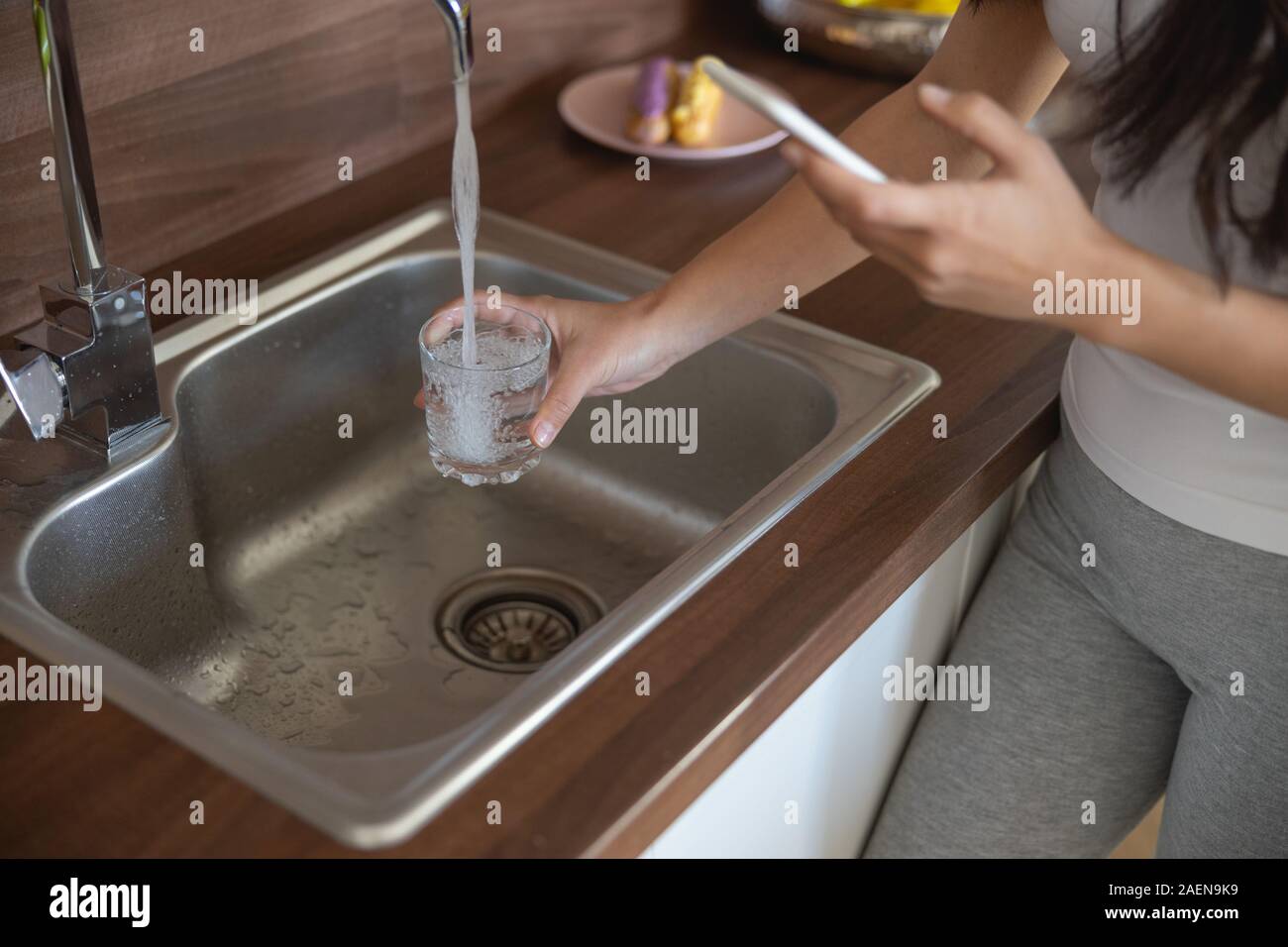 Lady drawing fresh water from the faucet Stock Photo Alamy
