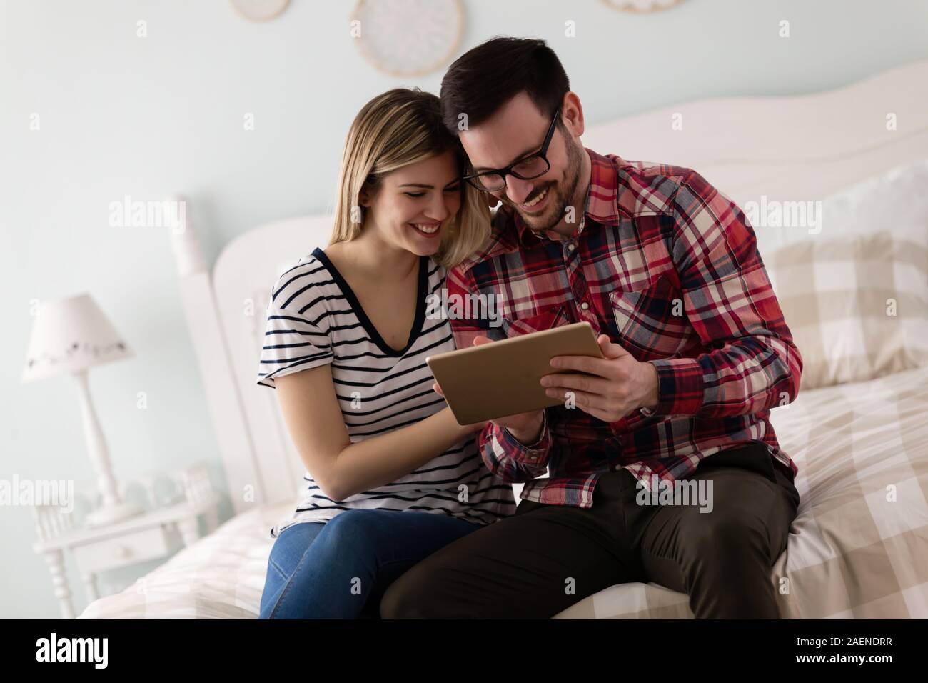 Young attractive couple using tablet in bedroom Stock Photo