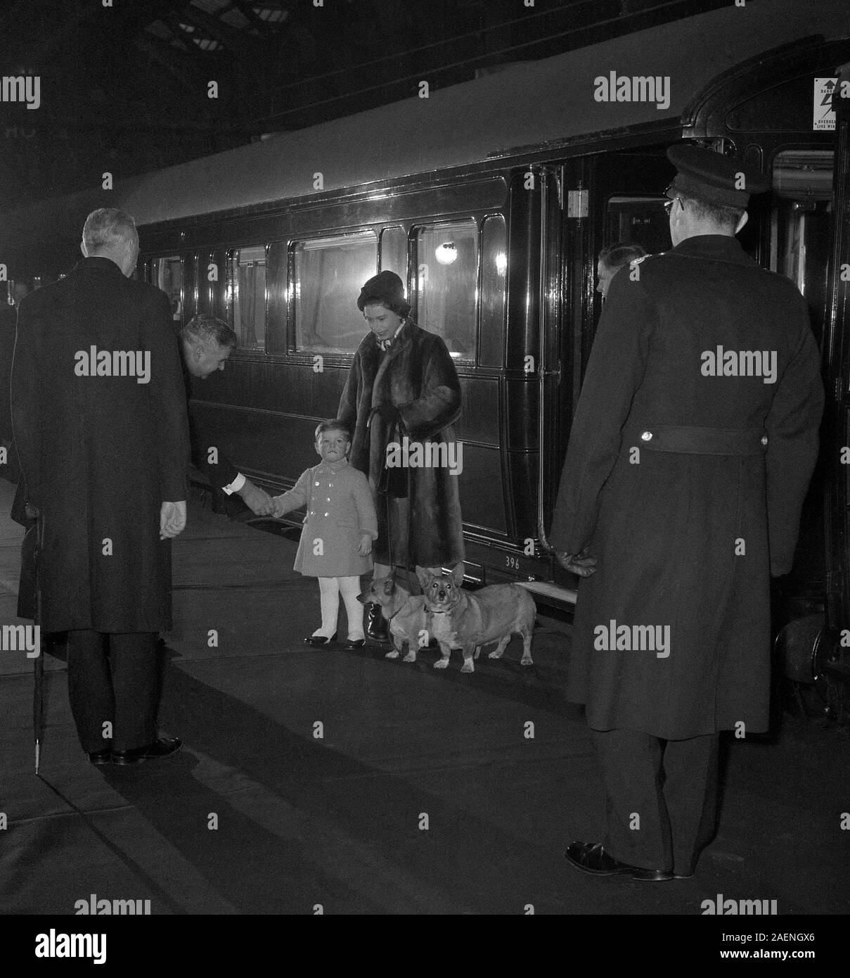 As Queen Elizabeth II takes charge of the two corgis, Prince Andrew shakes hands with the station master at Liverpool Street Station, London. The Queen had just returned to London with the Prince from Sandringham, where they had been for the Christmas holidays. Stock Photo