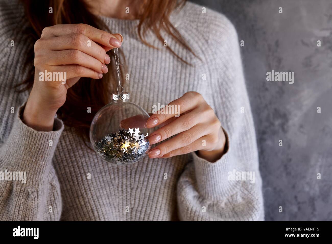 Woman holding Christmas glass ball with glistening star pailettes inside, holiday concept Stock Photo