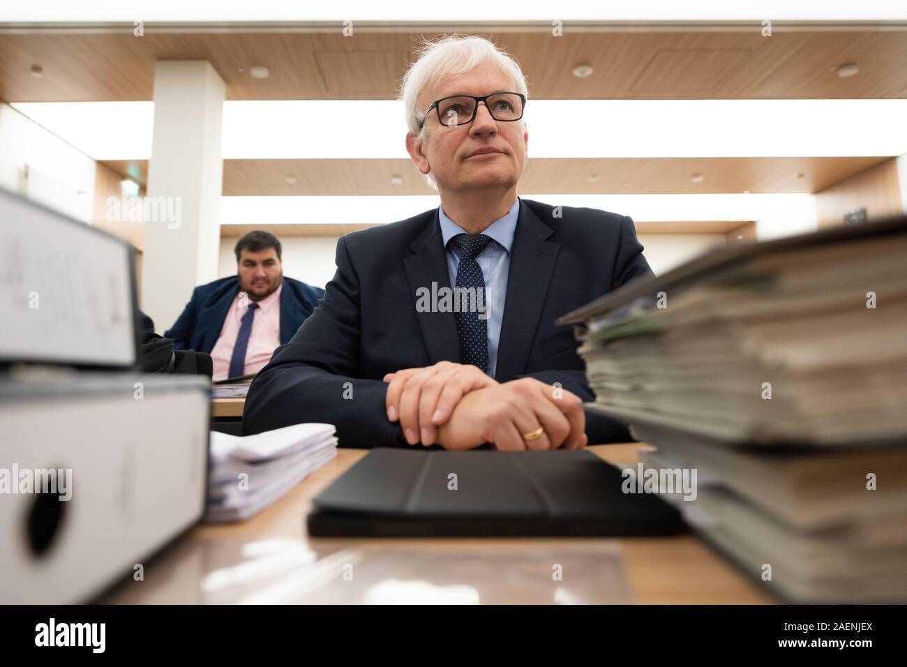 Kassel, Germany. 10th Dec, 2019. Jürgen Resch (front), Managing Director of Deutsche Umwelthilfe, sits between files in the Hessian Administrative Court before the trial begins. In an appeal against an action brought by Deutsche Umwelthilfe, the court is dealing with possible bans on diesel driving in the city of Frankfurt am Main. Credit: Swen Pförtner/dpa/Alamy Live News Stock Photo