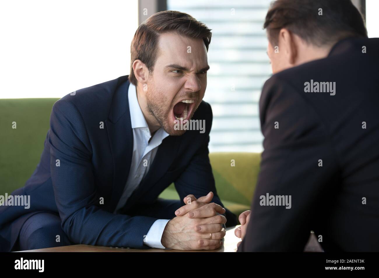 Angry businesswoman screaming at opponent, showing aggression at meeting Stock Photo